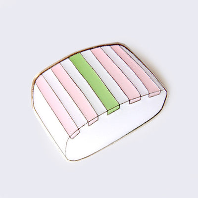 Enamel pin of a white suama mochi treat, with a green stripe in the middle and two pink stripes on either side.