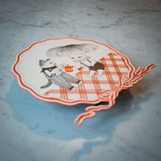 Illustration of a kind looking cat wearing pinstriped overalls, pouring coffee into a mug being held by a sitting figure with a large mushroom head. They are positioned on a plaid orange and white flooring. A circular orange striped bow surrounds the piece.