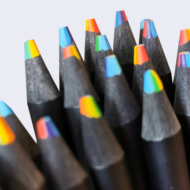 Close up of multiple black pencils with squared off rainbow writing tips.