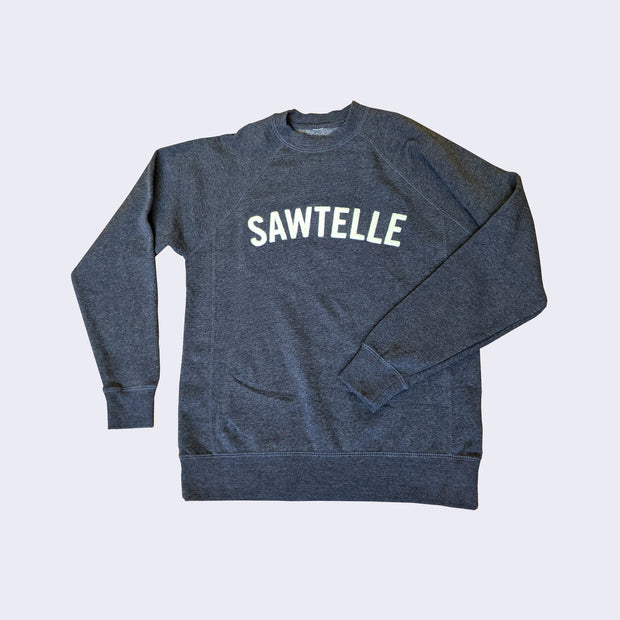 Long sleeve heather blue sweater with raglan style sleeves. "Sawtelle" is written in embroidered cream colored letter across the chest, in the upper center.