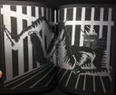 Open two page spread of a large aquatic looking alien laying with legs raised in a striped room.