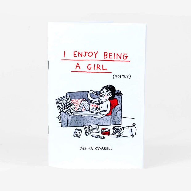 Staple bound zine on white paper featuring an illustration of a woman laying on her couch, watching TV on her laptop and eating chips. Title reads "I Enjoy Being a Girl" in red font and "mostly" written nearby in small parentheses.