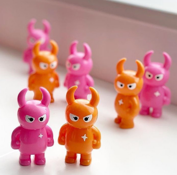 A window sill with many Big Boss Uamou figures, alternating between hot pink colored and a bright orange.
