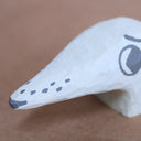 Small whittled wooden sculpture of a dog's head with a very long snout. It has painted on features, and looks off to the side nervously.