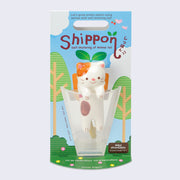 Ceramic calico cat, smiling and positioned over a small plastic cup. Its backing card features illustrations of plants and trees and reads "Shippon".