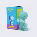 Simplified light teal character looking down at a similar shaped character who is wrapped around its leg. Behind it is its display box.
