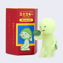 Simplified light yellow/green character holding a small vase in its hand, with a small similar shaped figure standing behind it. It stands next to a red display box.