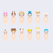 12 vinyl Kewpie babies, standing nude with different animal themed hood hats. Options are: hippo, horse, lion, peacock, dog, alpaca, bison, calico cat, cheetah, horned goat and blue gorilla.