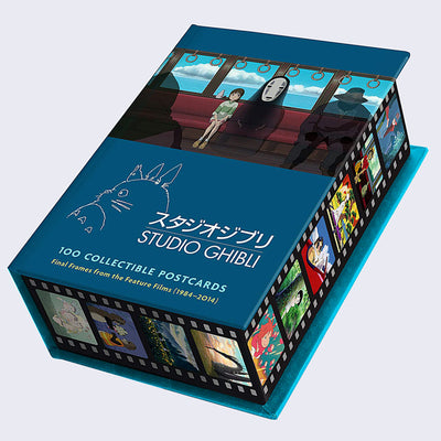Closed box of 100 Studio Ghibli postcards, featuring an illustration from Spirited Away of Chihiro and No Face sitting in a train car. Around the box is a film strip design, with various Ghibli art in each cell.