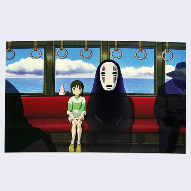 Postcard featuring art from Spirited Away of Chihiro and No Face sitting in a train car, next to smokey black spirits.