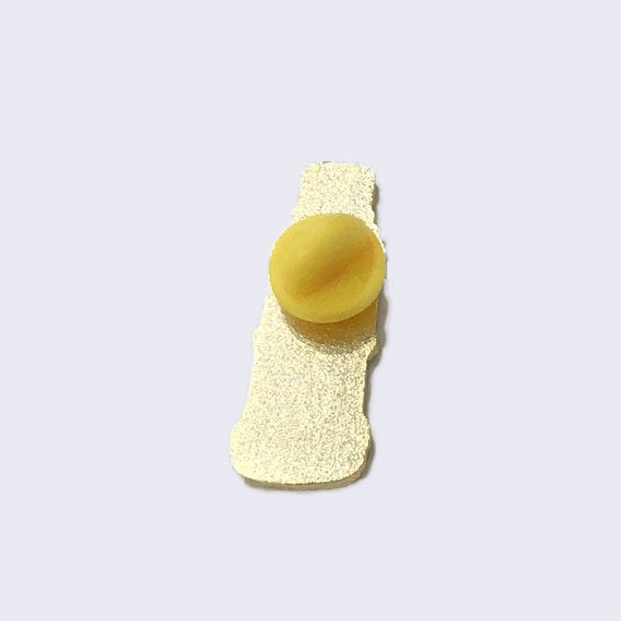 Back of enamel pin, with a yellow rubber pin backing.