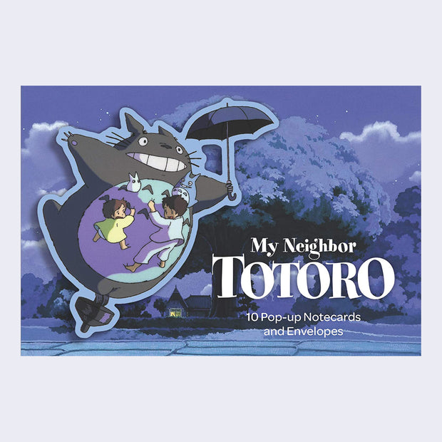 Box of postcards from My Neighbor Totoro, featuring a pop up style graphic of Totoro flying through the night sky with two small girls in pajamas on his stomach.