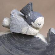 Wooden sculpture of Totoro in profile view, laying on his back with eyes closed, with a little girl with pigtails resting atop his belly. Piece is entirely greyscale.