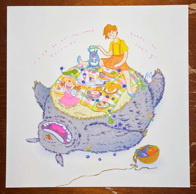 Risograph print of Totoro, laying on the ground on his back and smiling widely. Atop his fluffy stomach is a picnic set up with a wide variety of food and dust sprites accompanying Chibi Totoro and Mei and Satsuki from My Neighbor Totoro.