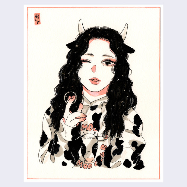 Illustration of a woman with long wavy black hair and small white horns, visible from the torso up. She is wearing a cow patterned hoody with a small illustration of a cow in the center. She holds a silver ring in between her fingers.