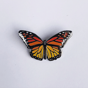 Gif of enamel monarch butterfly pin, one image is of the pin in light and the other is of the accents of the pin glowing in the dark.