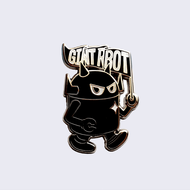 Gif of an enamel pin of a black robot with a silver outline, walking while holding a flag that says "Giant Robot." One image is of the pin in the light and one is of the pin glowing in the dark.