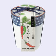 A white ceramic cup with blue dot patterning around the rim and a paper label that reads "Togarashi Chili Pepper" with illustrations of peppers. A blue string bundles the label and the cup.