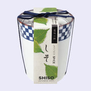 A white ceramic cup with blue dot patterning around the rim and a paper label that reads "Shiso Japanese Basil" with illustrations of leaves. A blue string bundles the label and the cup.