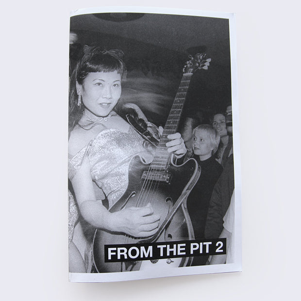 Zine cover reading "From the Pit 2" featuring a black and white photo of an Asian woman in a dress and nice jewelry playing a guitar in front of a close crowd.