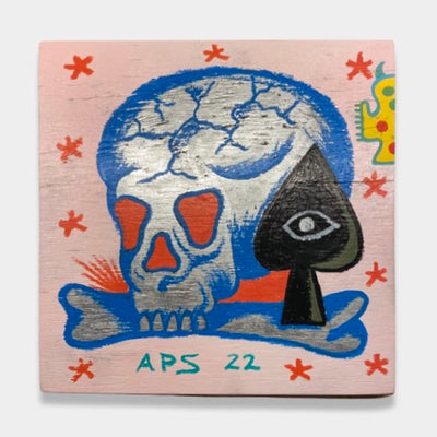 Tattoo style illustration of a silver skull with blue outlining. The skull lies on a bone with a black spade with a silver eye next to it. Background is light pink with simple red stars in a pattern. "APS 22" reads at the bottom.