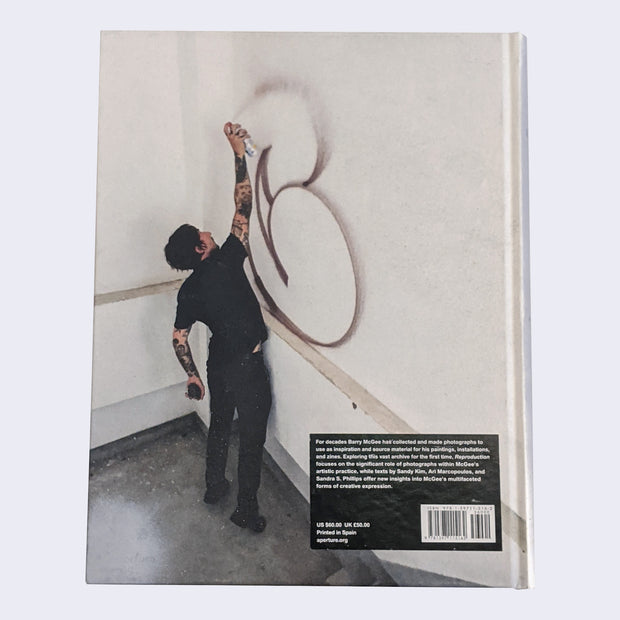 Back cover of the book showing a man spray painting a wall. It's of a letter C.