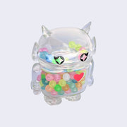 Soft clear vinyl figure with colorful round beads inside. Figure is shaped like a smaller Big Boss Robot, with a bigger head than normal and two black eyes with sparkles as pupils. A red heart is on its upper right chest.