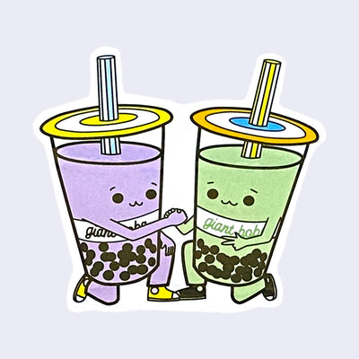 White cut out sticker with a smiling taro boba kneeling and clasping hands with a green tea boba in the same pose. "Giant Robot" is written across both cups.