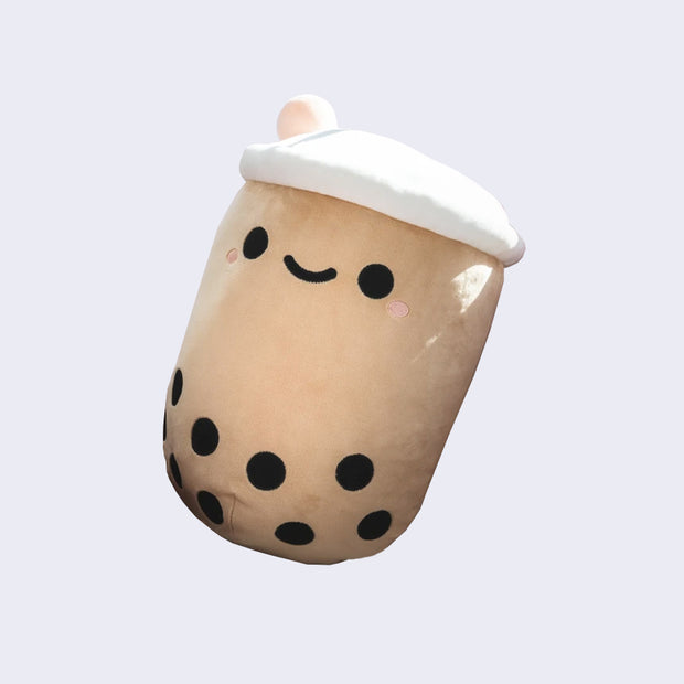 Rounded squishy brown plush shaped like a boba tea cup, with a cute kawaii smile and a pink straw coming out of the top.