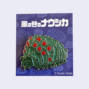 A brooch of a large, green grub bug  with many legs and glittery red dots as eyes.