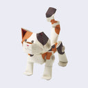 Small calico cat sculpture made out of paper pipes, with a smiling face and tall tail.