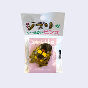 Enamel pin of Catbus with a slight smile, facing head on and looking down. On a light pink backing card with Japanese writing, in a decorated plastic bag.