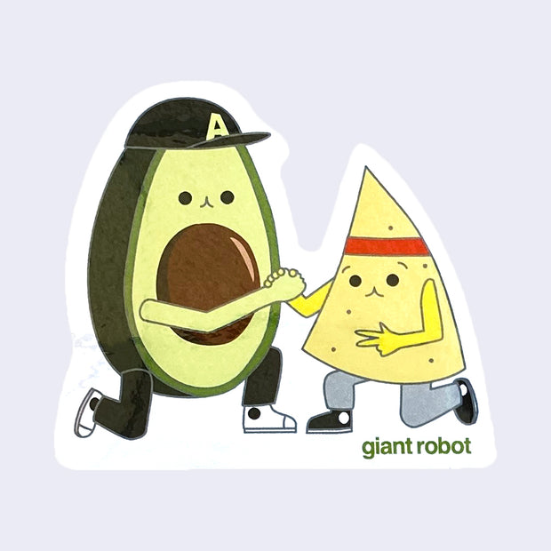 White cut out sticker of an illustrated smiling avocado, wearing white sneakers and a baseball cap. It kneels and clasps hands with an illustrated tortilla chip, wearing gray pants, black sneakers and a red headband. "Giant Robot" is written in lowercase green font below the chip.