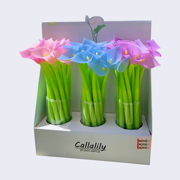 Pen display, "Callalily" written along the box and 3 clear cups hold bright pink, periwinkle, and violet lily flower topped pens.