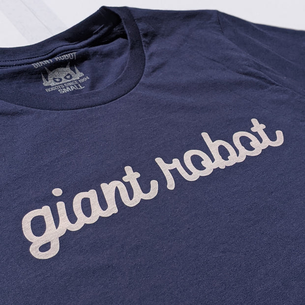 Close-up of dark blue t-shirt facing front with text in cursive that says giant robot.