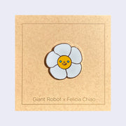Enamel pin of a daisy with a smiling face