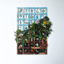 Paper collage of a grid, top half blue with different blue and white imagery in each grid square, such as clouds, birds and leaves. Around halfway, an upward slope collage of lush greenery, many leaves, branches and flowers, the other half of the grid is brown with black squares. Within each square is various earth toned imagery, such as mushrooms, squirrels, fauna and flora.