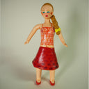 Paper clay sculpture of a woman with slicked back braid, a see through top and a long red skirt.