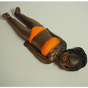 Figure of a black woman in an orange bikini, laying on the ground and sunbathing.