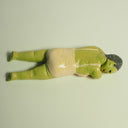 Clay sculpture of an old woman with green skin wearing a one piece bathing suit and laying on her stomach, as if sun bathing.
