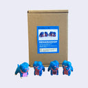 4 small, blue soft vinyl bulldogs with their mouths open and tongues out. They each have bright pink eyes and pink fabric around their neck, some with writing, and some blank. They stand in front of their product packaging.