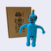 Blue painted soft vinyl figure of a nude man with glasses. He is balding with some facial hair and has a gold tipped penis atop his head. His nipples are gold and his own penis is also gold tipped. One of his hands is formed into a peace sign.