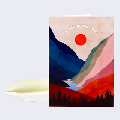 Greeting card with full bleed illustration of tall, colorful mountains leading down into a lake with trees in the foreground. A red sun hangs in the middle and "To New Adventures" is written across the top.