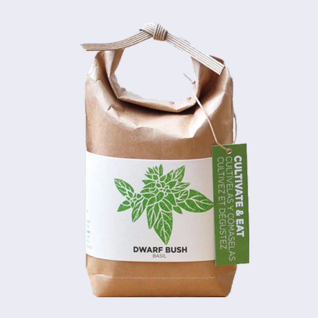 Brown paper sack, folded and tied with a paper tie and a green hang tag that reads "Cultivate & Eat". Wrapped around is a cream sheet, with an illustration of basil leaves. "Dwarf Bush Basil" is written on the bottom.