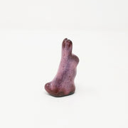  Aubergine purple ceramic rabbit, with very simplistic body shapes and no facial features. It is positioned upright with its ears straight up and small rounded tail.