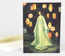 Greeting card with a full bleed illustration of a woman wearing a long flowing robe and holding a red lantern, standing in a dark forest setting. At her feet is a small crocodile and all around her are bright colored paper lanters.