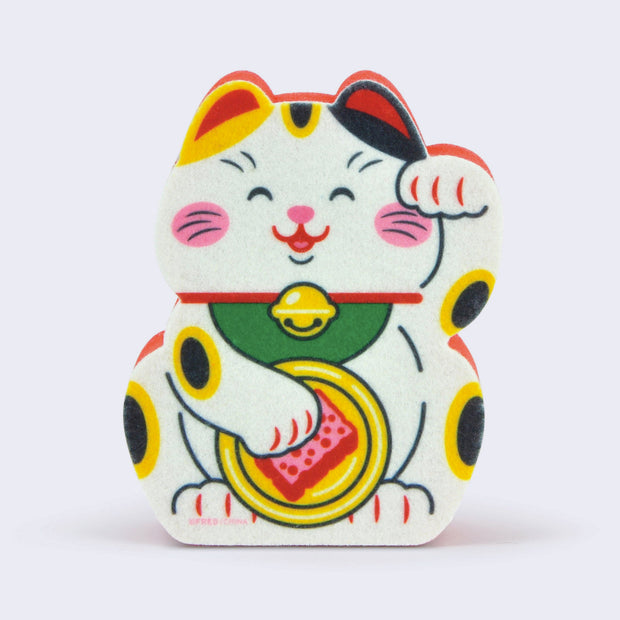 Die cut sponge featuring an illustration of a traditional Japanese maneki, white with yellow and black spots, one of its paw raised and the other washing a dish with a pink sponge.