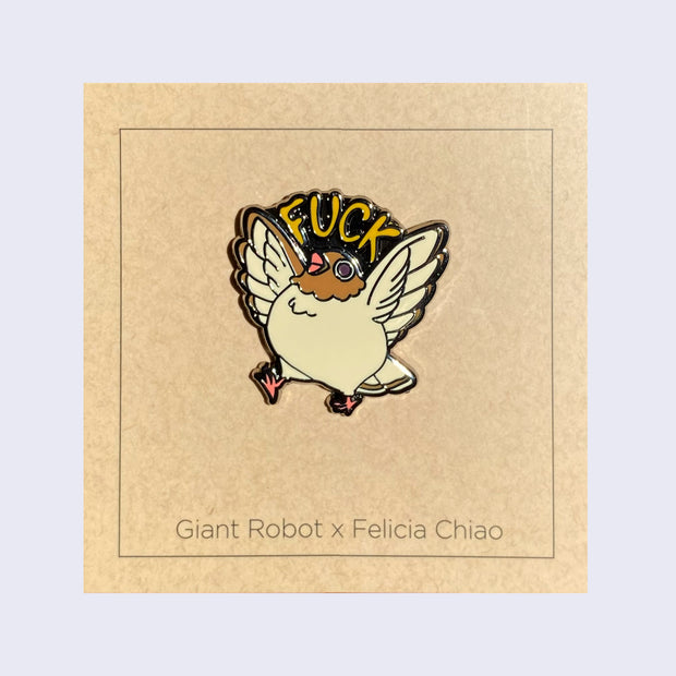 Enamel pin of a chubby, brown pigeon with its wings spread and beak open. "Fuck" is written over its head. 