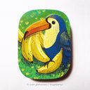 Painting of a blue toucan sitting atop of several bananas with a green grass.