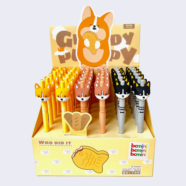 Yellow cardboard pen display, with a large illustration of a chubby corgi holding a taiyaki with "Greedy Puppy" written behind it. It displays 36 pens with simplified corgi heads as pen toppers.